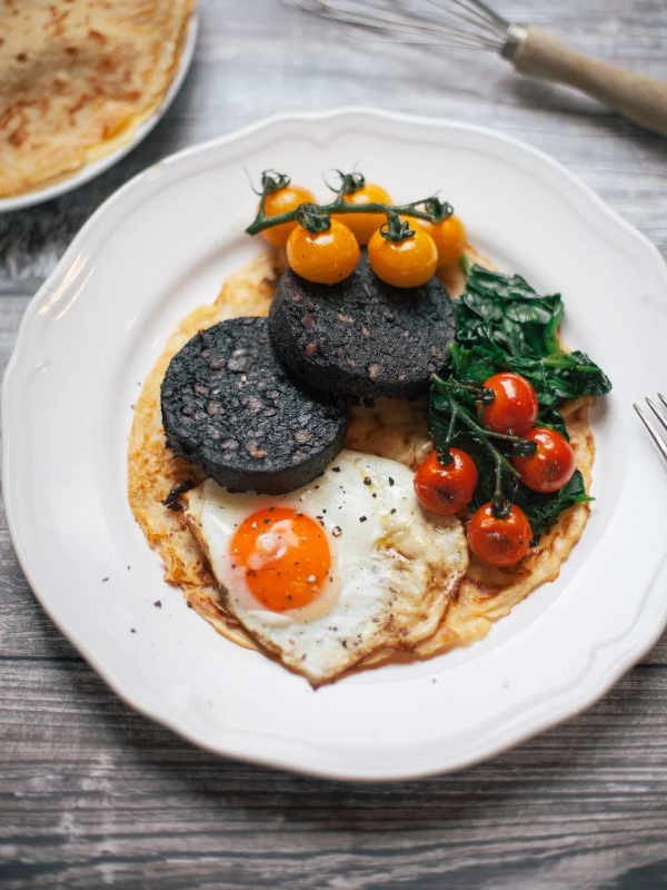 Black pudding pancakes with charred tomatoes, wilted spinach & fried eggs